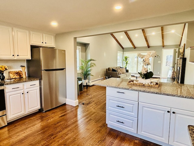 kitchen featuring light stone counters, lofted ceiling with beams, white cabinetry, freestanding refrigerator, and dark wood finished floors