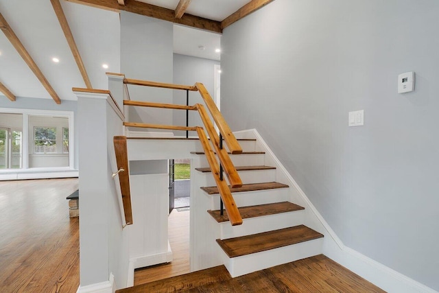 staircase with baseboard heating, wood finished floors, baseboards, and beam ceiling