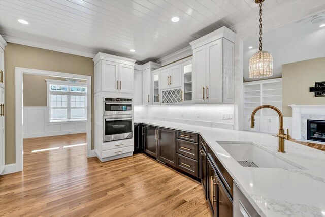 kitchen with sink, white cabinetry, hanging light fixtures, and double oven