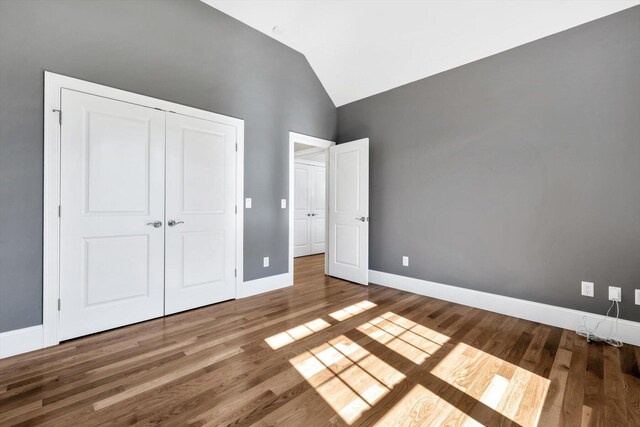 unfurnished bedroom with a closet, vaulted ceiling, and wood-type flooring