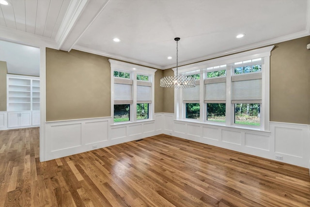 unfurnished dining area featuring crown molding, wood-type flooring, beamed ceiling, and an inviting chandelier