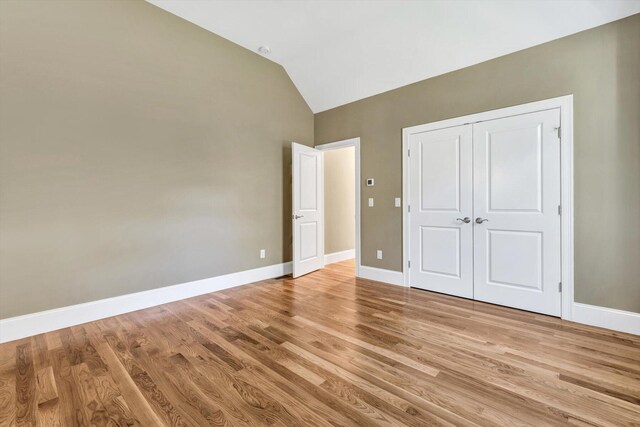 unfurnished bedroom with a closet, light hardwood / wood-style floors, and lofted ceiling