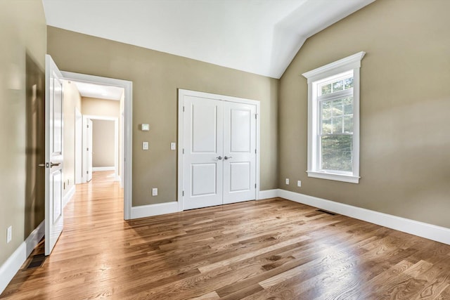 unfurnished bedroom with light hardwood / wood-style flooring, a closet, and vaulted ceiling