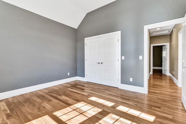 unfurnished bedroom with light hardwood / wood-style floors, a closet, and lofted ceiling