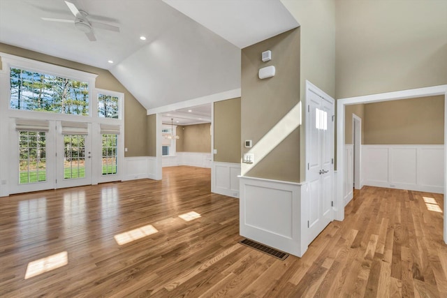 unfurnished living room with ceiling fan, high vaulted ceiling, and light wood-type flooring