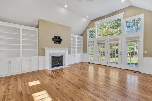 unfurnished living room featuring a premium fireplace, vaulted ceiling, and light hardwood / wood-style flooring