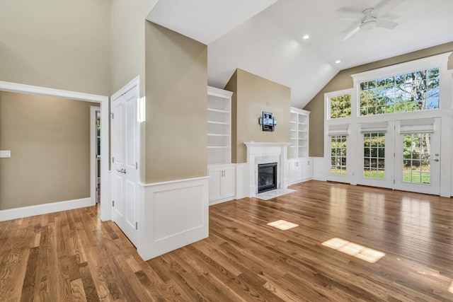 unfurnished living room featuring hardwood / wood-style flooring, ceiling fan, built in shelves, and a premium fireplace