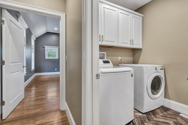 laundry area with washing machine and dryer, dark hardwood / wood-style flooring, and cabinets