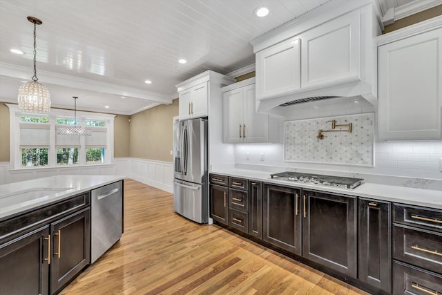 kitchen featuring pendant lighting, light hardwood / wood-style flooring, white cabinetry, decorative backsplash, and stainless steel appliances