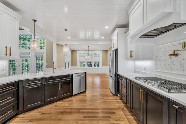 kitchen featuring sink, stainless steel appliances, white cabinetry, and decorative light fixtures