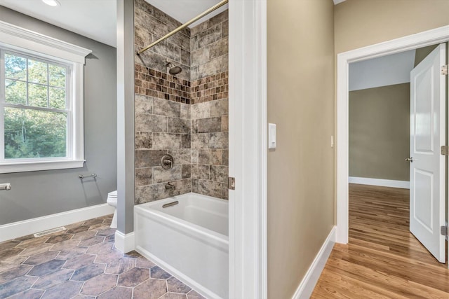 bathroom featuring toilet, tiled shower / bath, and wood-type flooring