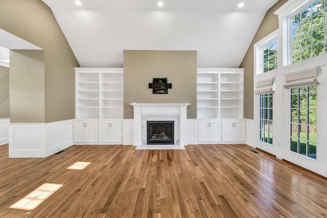 unfurnished living room with light wood-type flooring, lofted ceiling, and a fireplace