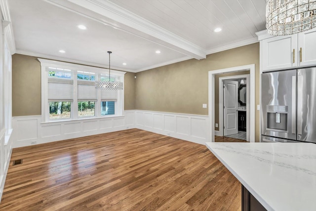 unfurnished dining area with wood-type flooring, a notable chandelier, ornamental molding, and beamed ceiling