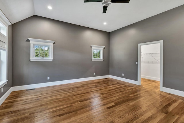 spare room with vaulted ceiling, a healthy amount of sunlight, and hardwood / wood-style floors