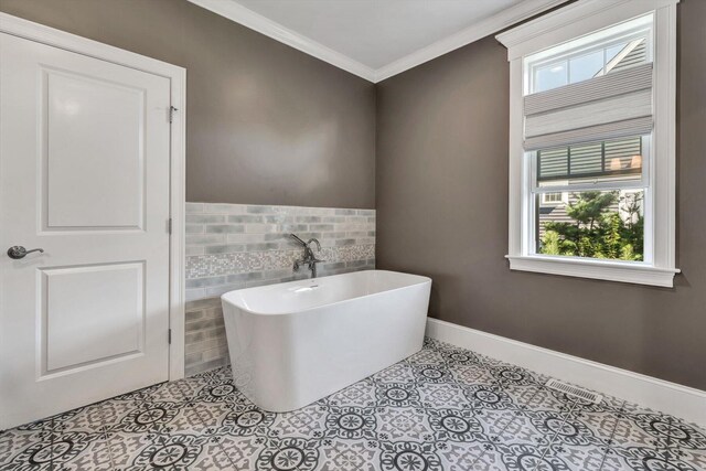 bathroom featuring a healthy amount of sunlight, a tub to relax in, tile patterned floors, and ornamental molding