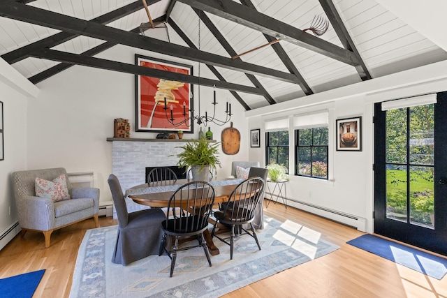 dining room featuring a brick fireplace, baseboard heating, beam ceiling, and light hardwood / wood-style floors