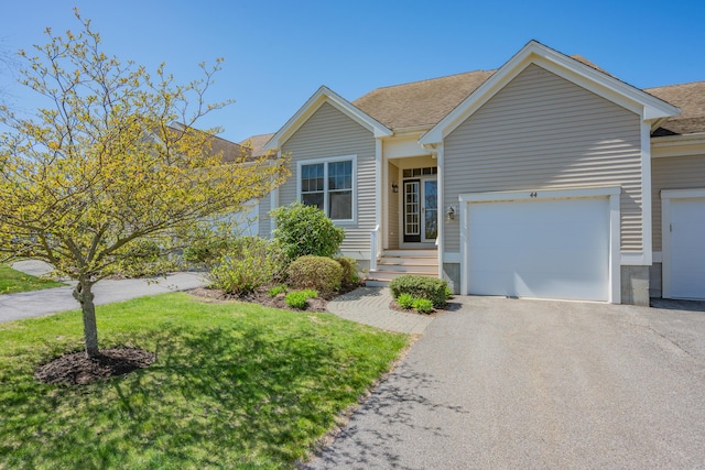 ranch-style home featuring a shingled roof, an attached garage, driveway, and a front lawn
