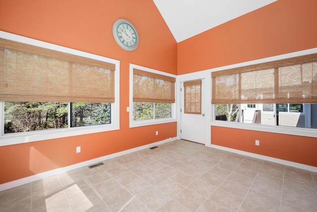 spare room featuring high vaulted ceiling, visible vents, baseboards, and tile patterned flooring