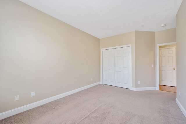 unfurnished bedroom with baseboards, light carpet, and a closet