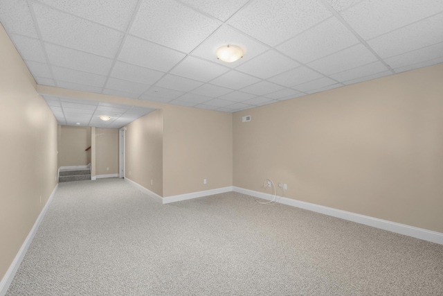 finished below grade area with stairway, carpet floors, baseboards, and a paneled ceiling