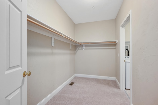 walk in closet with carpet floors, visible vents, and washer / dryer