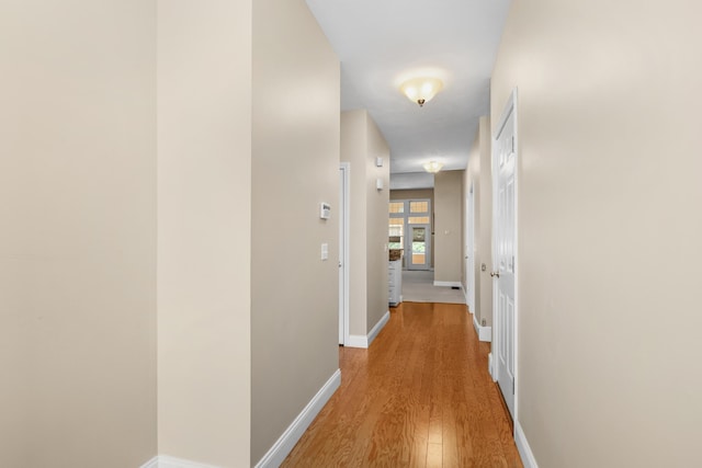 hallway featuring light wood-style floors and baseboards