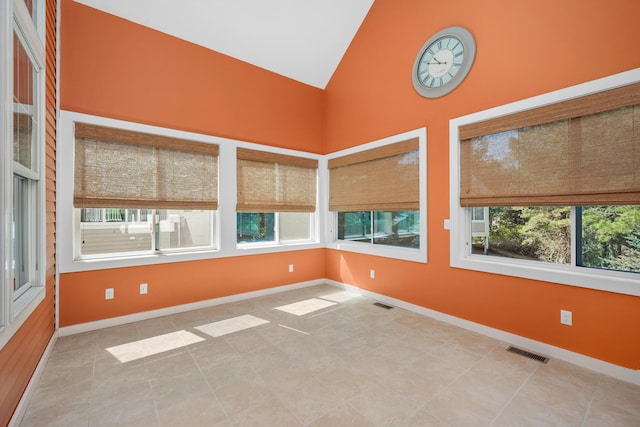 tiled spare room featuring visible vents, baseboards, and high vaulted ceiling
