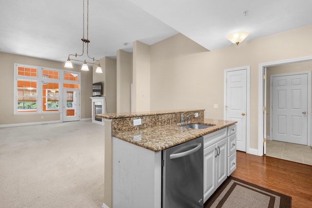kitchen with light stone countertops, baseboards, a sink, dishwasher, and decorative light fixtures