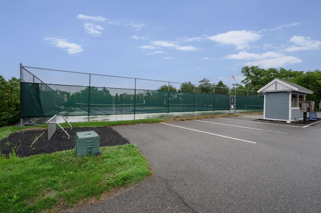 uncovered parking lot featuring fence and a tennis court