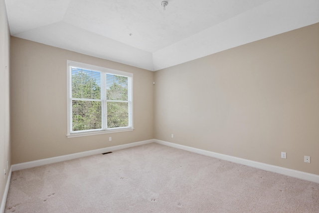 unfurnished room with baseboards, visible vents, vaulted ceiling, and light colored carpet