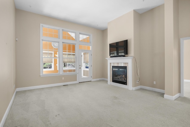unfurnished living room featuring baseboards, carpet flooring, and a glass covered fireplace