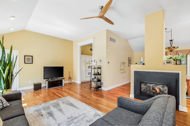 240 Surf Dr, Mashpee, MA 02649 - living area with vaulted ceiling, ceiling fan, wood finished floors, a glass covered fireplace, and baseboards