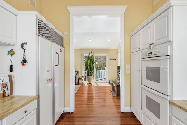 240 Surf Dr, Mashpee, MA 02649 - kitchen with double oven, paneled fridge, dark wood-style flooring, white cabinets, and light countertops