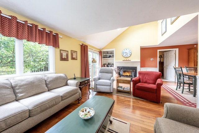 151 Leisure Green Dr N, Mashpee, MA 02649 - living area with a glass covered fireplace, lofted ceiling, wood finished floors, and built in features