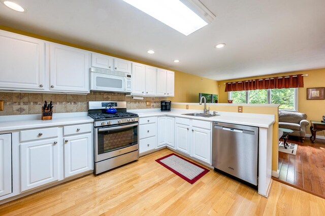 151 Leisure Green Dr N, Mashpee, MA 02649 - kitchen with appliances with stainless steel finishes, a peninsula, light wood-style floors, light countertops, and decorative backsplash