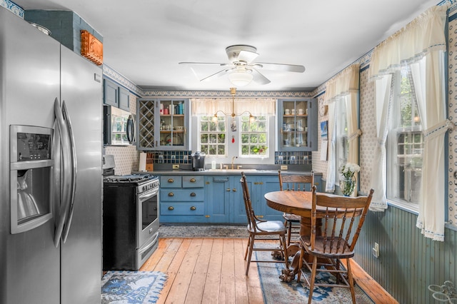 64 Riverside Dr, West Harwich, MA 02671 - kitchen featuring appliances with stainless steel finishes, a sink, glass insert cabinets, a ceiling fan, and wallpapered walls