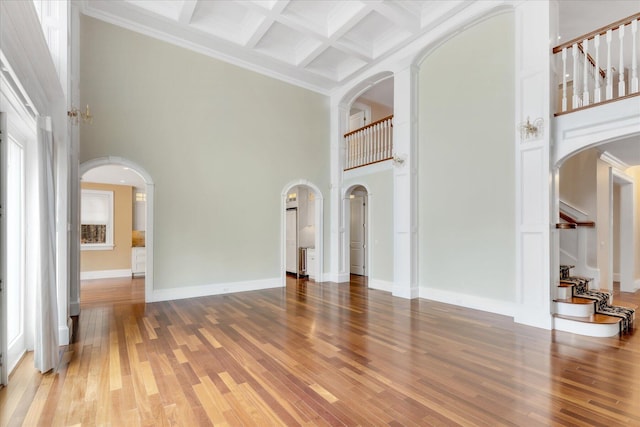 24 Pleasant Park Dr, Mashpee, MA 02649 - unfurnished living room featuring arched walkways, a towering ceiling, wood finished floors, beam ceiling, and coffered ceiling