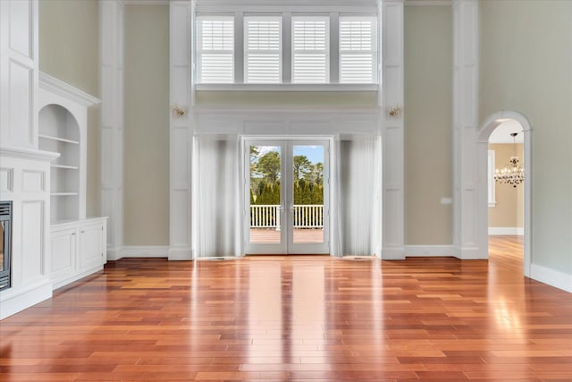 24 Pleasant Park Dr, Mashpee, MA 02649 - unfurnished living room with a high ceiling, a glass covered fireplace, a chandelier, light wood finished floors, and arched walkways