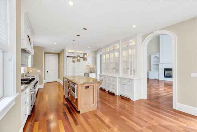 24 Pleasant Park Dr, Mashpee, MA 02649 - kitchen with stainless steel appliances, light wood-style floors, glass insert cabinets, recessed lighting, and light stone counters