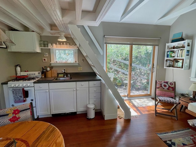 kitchen featuring a sink, white gas stove, dark countertops, white cabinets, and dark wood-type flooring