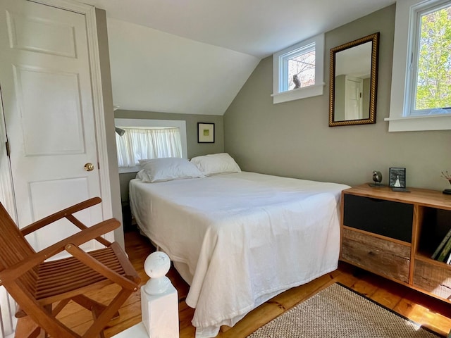 bedroom featuring wood finished floors and lofted ceiling
