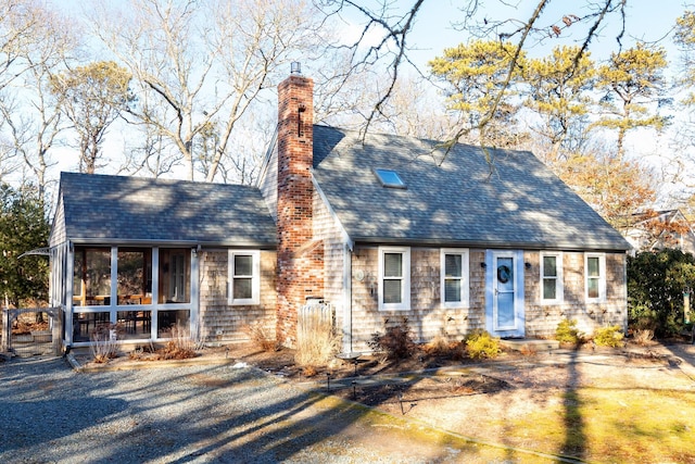 view of front facade with roof with shingles, a chimney, and a sunroom