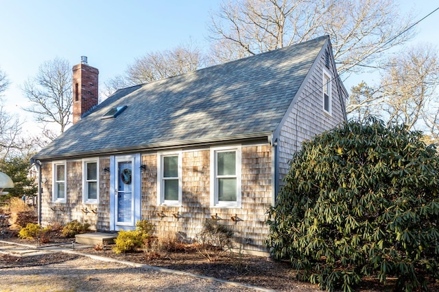 view of front of property with a shingled roof and a chimney