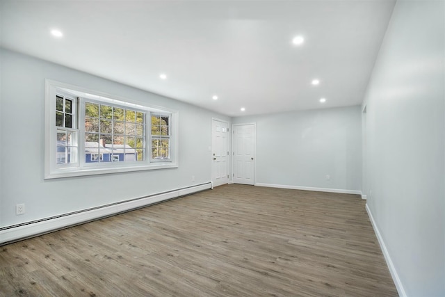 spare room featuring baseboard heating, recessed lighting, baseboards, and wood finished floors