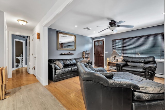 living room featuring ceiling fan, baseboard heating, and light hardwood / wood-style floors