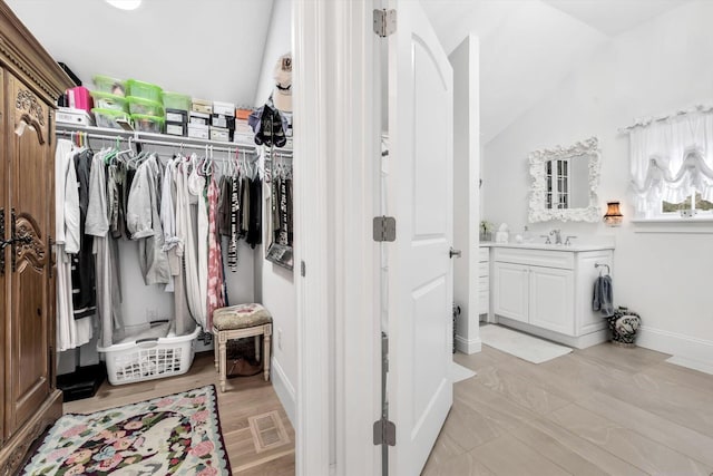 interior space with wood-type flooring, vanity, and lofted ceiling