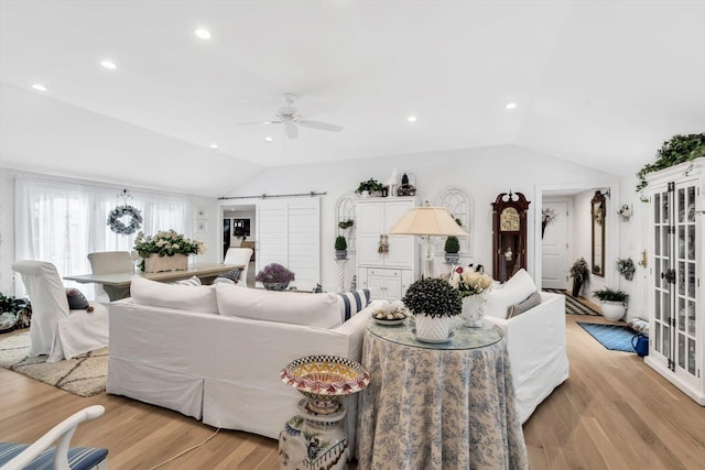 living room featuring ceiling fan, light hardwood / wood-style flooring, and lofted ceiling