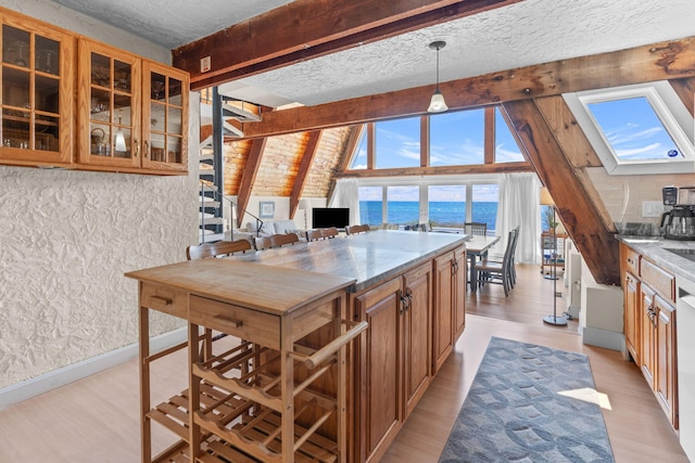 133 Breakwater Shores Dr, Hyannis, MA 02601 - kitchen with brown cabinets, light wood-style floors, glass insert cabinets, and a textured ceiling