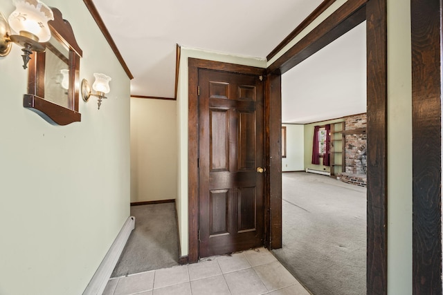 corridor featuring crown molding, light tile patterned flooring, light colored carpet, and baseboards