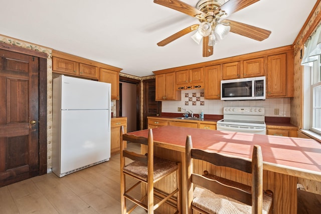 kitchen with white appliances, brown cabinets, tasteful backsplash, and a sink